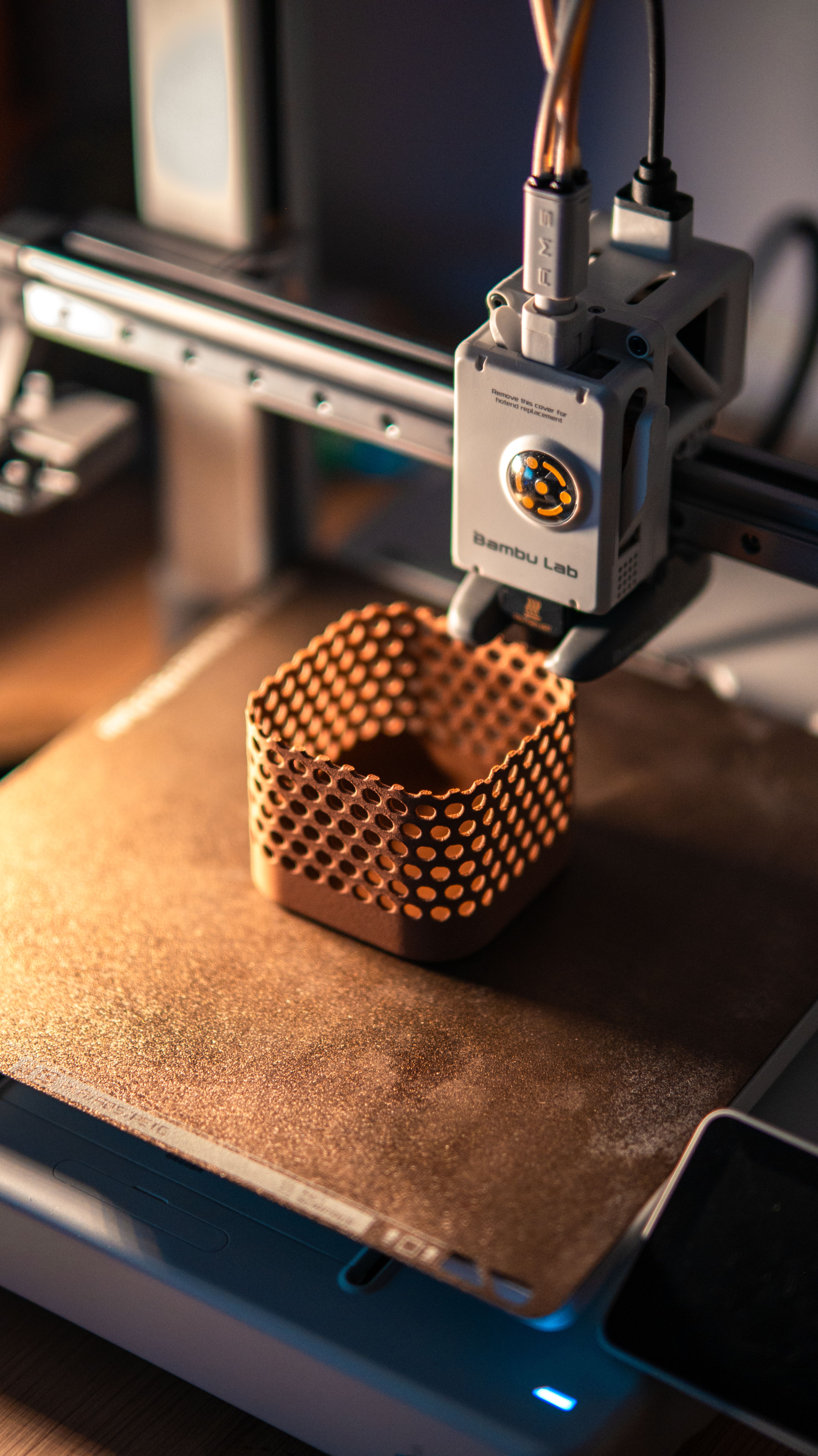 Bambu Lab printer mid-print — honeycomb structure in warm golden light